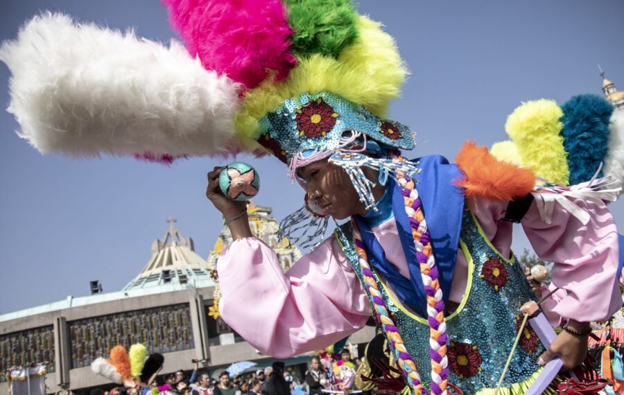 Danzante con penacho de plumas y sonaja frente a la Basílica