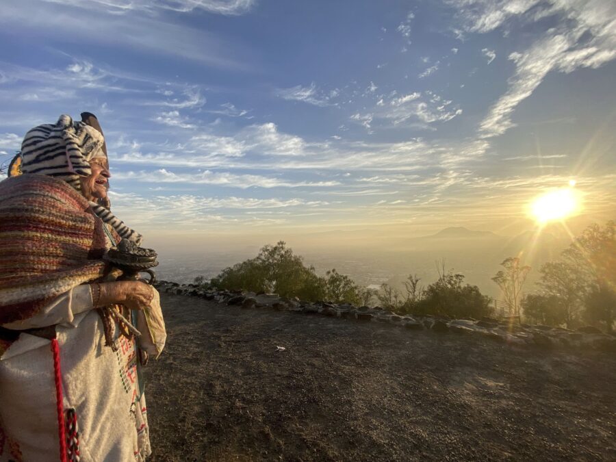 Una mujer envuelta en un rebozo mira el amanecer sobre el valle