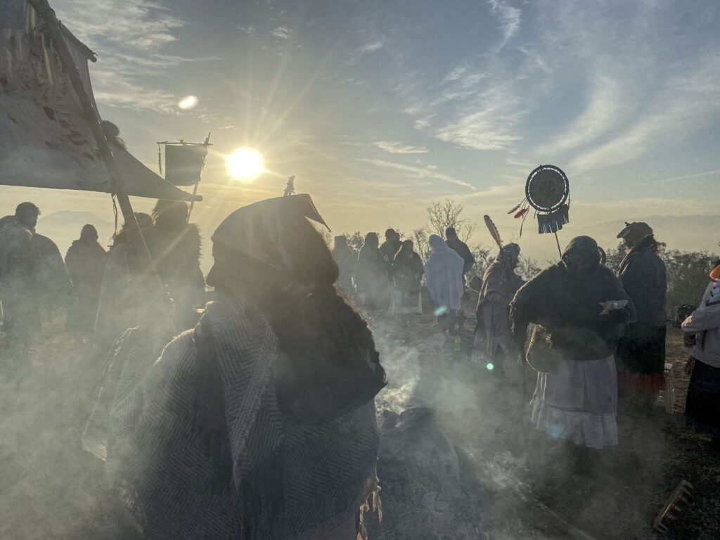 Participantes de la ceremonia entre el humo del copal, a contraluz del sol naciente