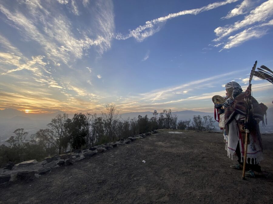 Un participante con estandarte al borde del cerro bajo un cielo con nubes